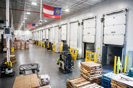 Interior view of a Airsun Express Logistics facility in Atlanta, Georgia, featuring a modern cold storage warehouse with multiple loading docks and efficient forklift operations.