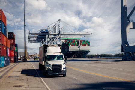 A Airsun Express Logistics truck at a bustling port, surrounded by shipping containers and cranes, showcasing seamless integration of cold storage and global logistics.