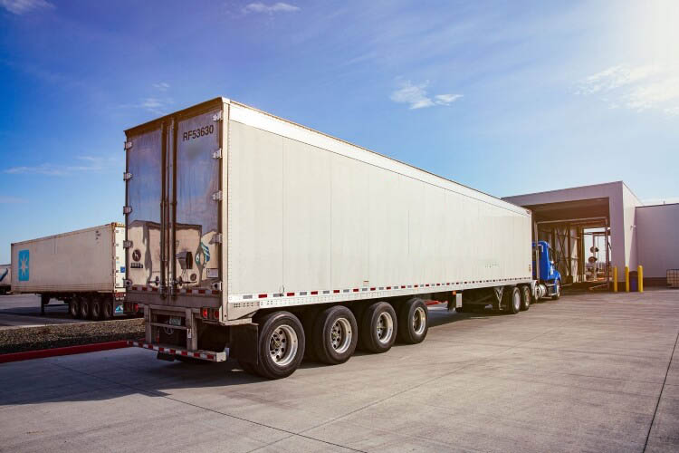 Airsun Express refrigerated trucks at a loading dock under a bright sky, highlighting the company's commitment to maintaining the cold chain integrity in food logistics.