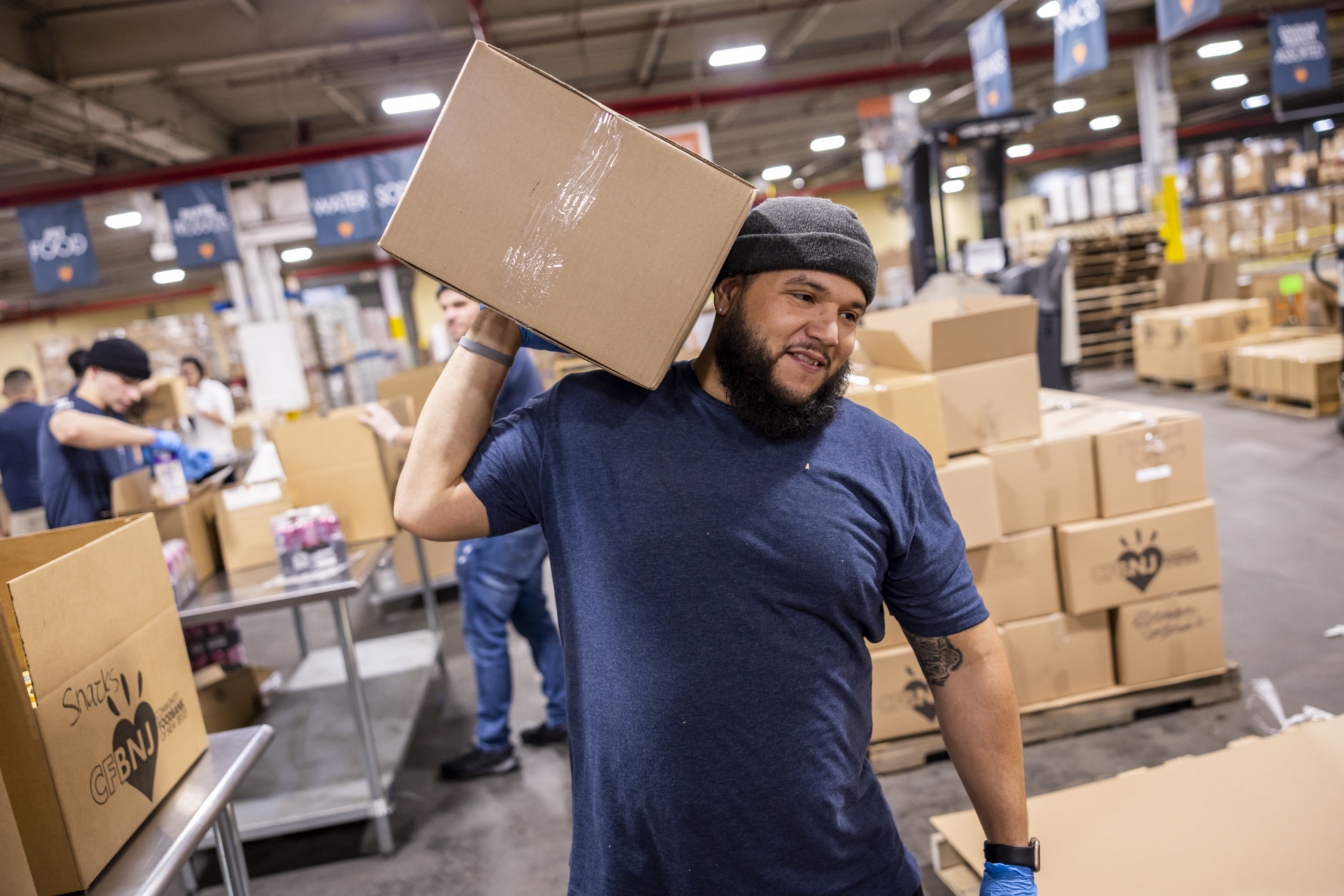 Man in Volunteer shirt living a box at a Foundation for Good event