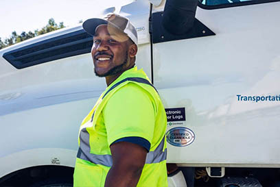 Smiling driver in high-visibility vest standing beside a Airsun Express Transportation truck, representing the dedicated workforce behind efficient food supply chain logistics.