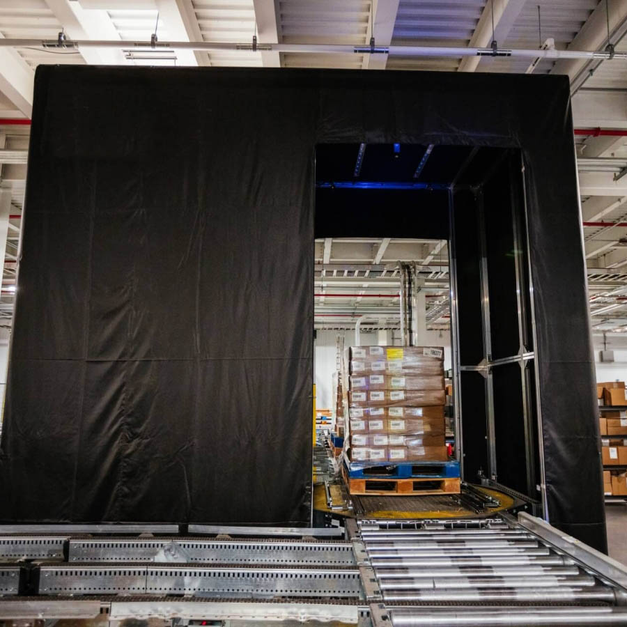 A neatly stacked pallet positioned on a Airsun Express Eye conveyor system in a clean, well-organized, automated cold storage warehouse, with safety guardrails and scanning stations in the vicinity.