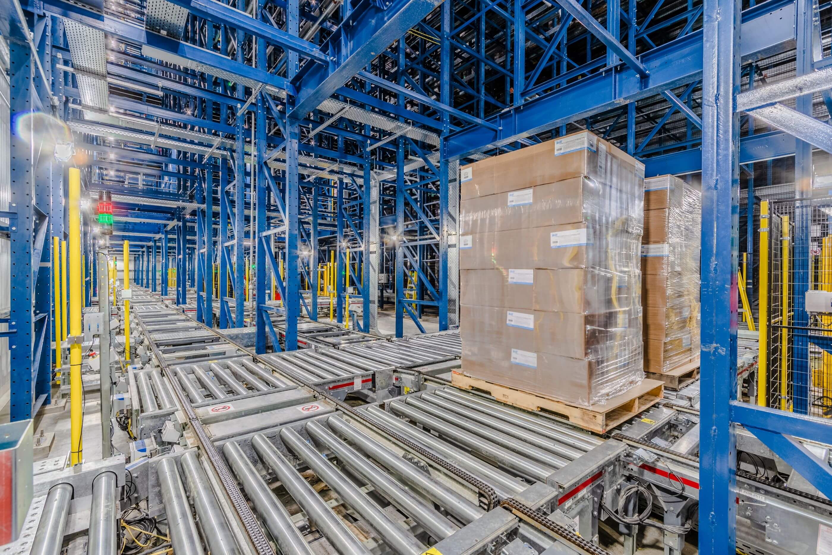 Airsun Express Sunnyvale automated warehouse interior with conveyor belts transporting shrink-wrapped pallets, flanked by tall blue steel racks.