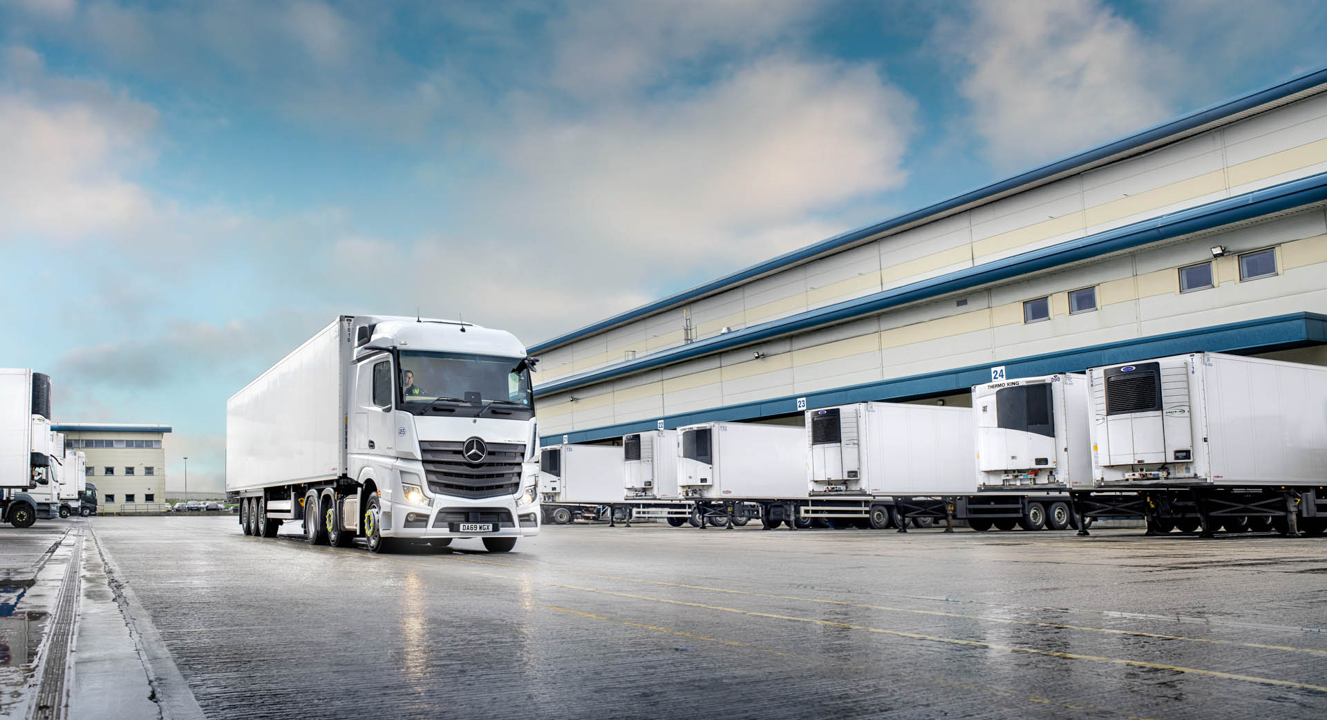 A Airsun Express truck driving past a fleet of parked Airsun Express trucks outside a Airsun Express warehouse.