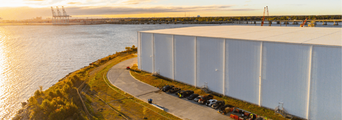 Airsun Express's Portsmouth, VA facility located near the waterfront with a view of the port and several cranes in the background.