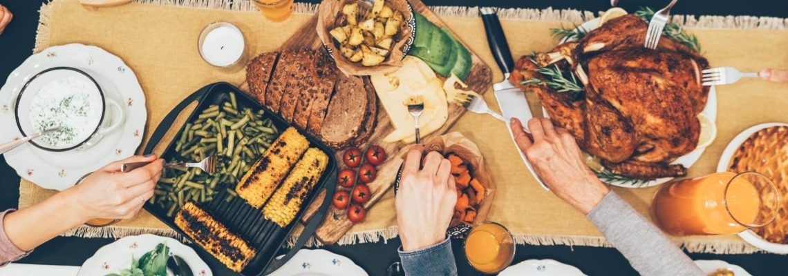 Top view of a family-style dinner table with roasted turkey, grilled vegetables, fresh salads, bread, and fruits, highlighting the theme of togetherness and food sharing for World Food Day.