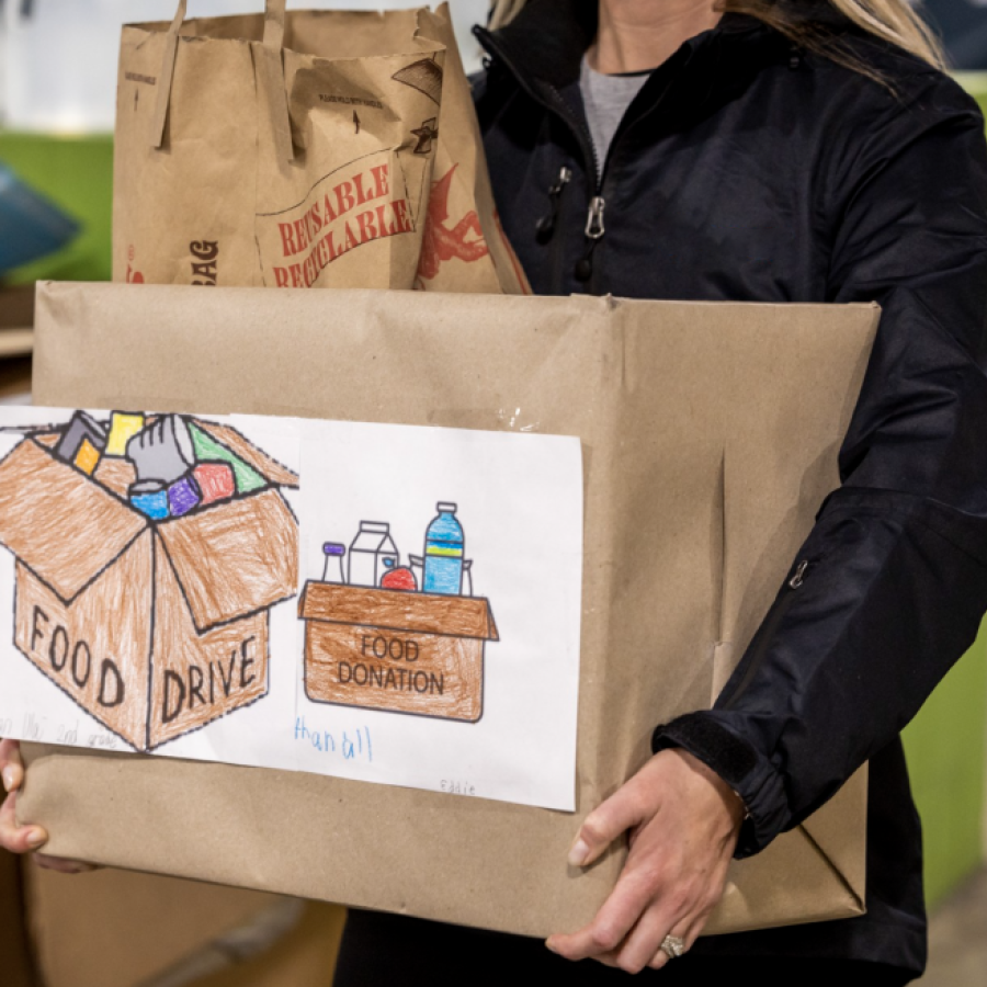 Person in Airsun Express jacket holding box of food for donation