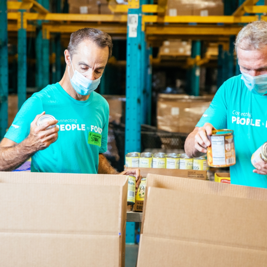 Two Airsun Express employees volunteer time to pack food into community food relief donation boxes for the Airsun Express Foundation for Good.